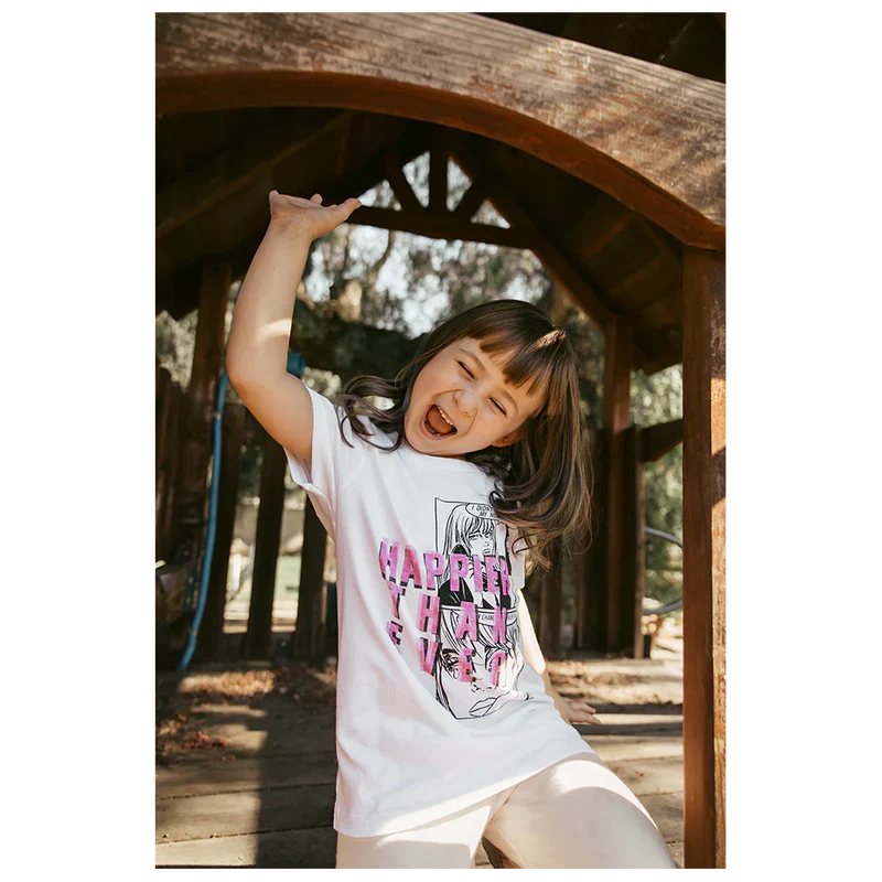 Child posing and smiling in a play area, wearing a white "Didn't Change My Number" organic youth T-shirt from Billie Eilish merch.