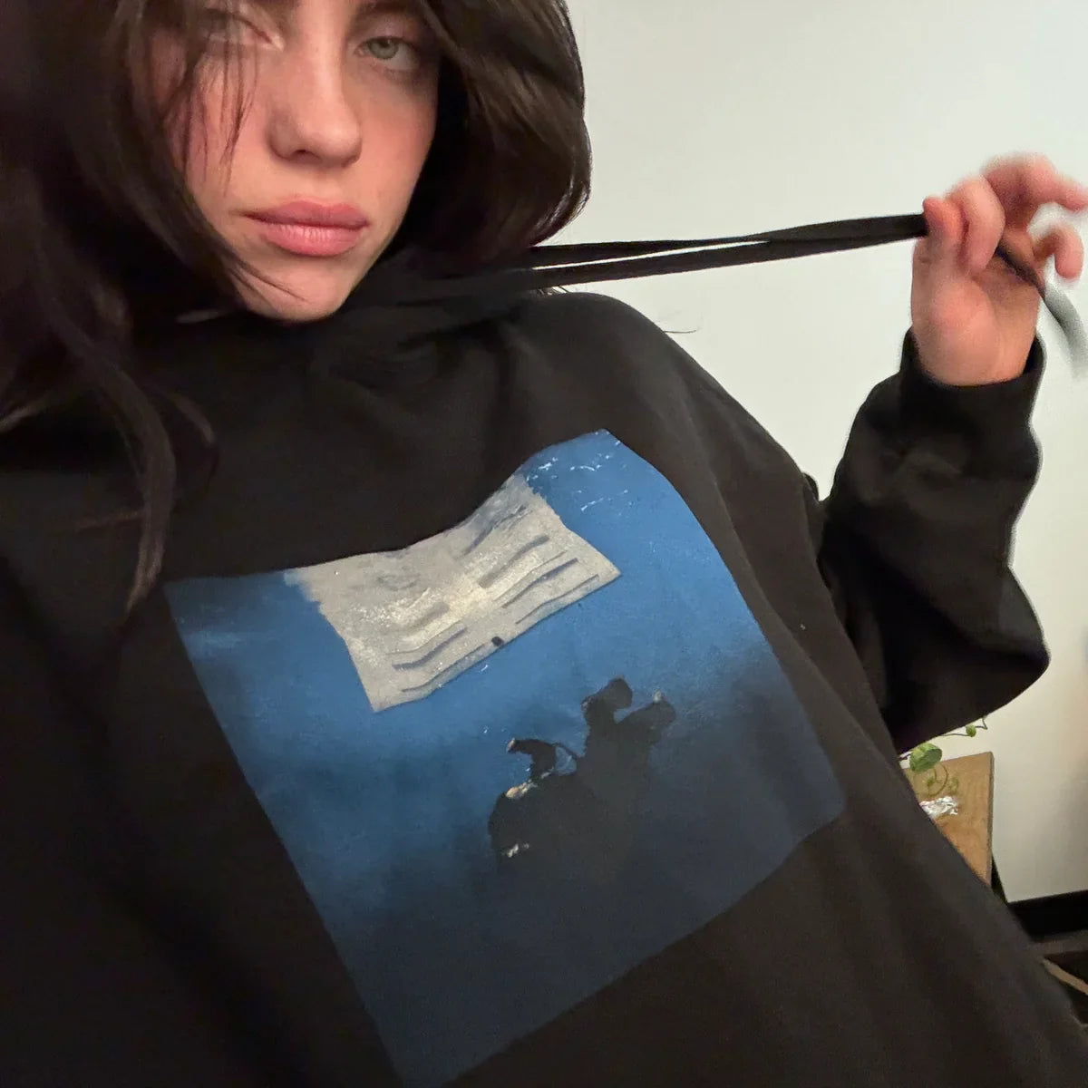 Billie Eilish wearing the Hit Me Hard And Soft Black Cover Pullover Hoodie featuring a cover art print on a black hoodie